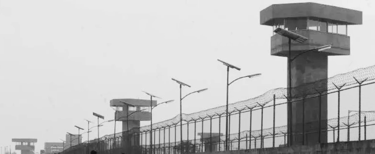 Muro exterior de un penal federal de máxima seguridad con alambrada y una torre de vigilancia.